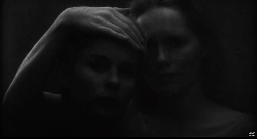 Sehr dunkles halbnahes Bild von zwei Frauengesichtern, von denen eine Frau den Kopf der anderen hält